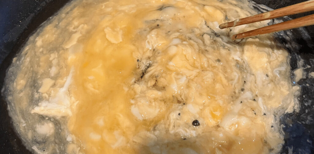 フライパンにごま油を加えて軽く混ぜ、さらに溶き卵を流し入れてゆっくりかき混ぜる